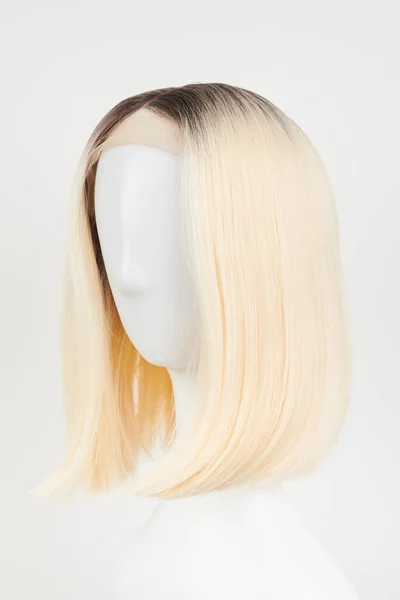 天然的金发碧眼的假发戴在白色的人体模特头上 用白色背衬把塑料假发架剪成中等长度的头发 — 图库照片