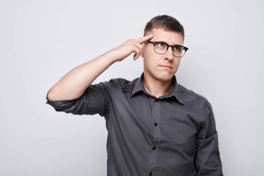 Kafasına dokunan tişörtlü zeki bir adamın portresi şüphenin beyaz stüdyo arka planında kopya alanı ile izole edilmiş seçimler olduğunu düşünüyor.