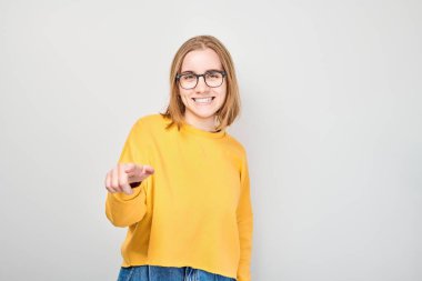 Kendine güvenen öğrenci portresi beyaz stüdyo arka planında izole edilmiş kamerayı işaret ediyor. Hoş geldin jesti, takım konseptimize katıl.