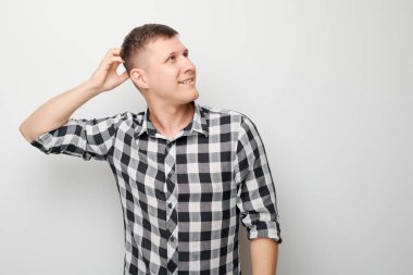 Kafasına dokunan tişörtlü zeki bir adamın portresi şüphenin beyaz stüdyo arka planında kopya alanı ile izole edilmiş seçimler olduğunu düşünüyor.