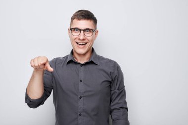 Kendine güvenen bir adamın portresi beyaz stüdyo arka planında izole edilmiş kamerayı işaret eder. Hoş geldin jesti, takımımıza katıl.