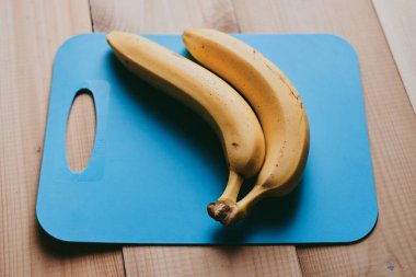 Ahşap mutfak masasında bir grup muzun yakın plan fotoğrafı.