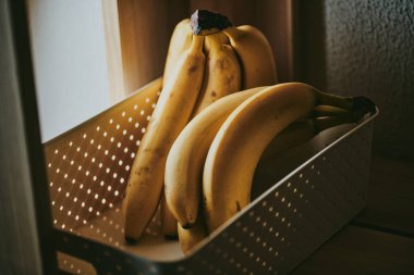 Arka planda bir sepetin içinde bir grup muzun yakın çekimi.