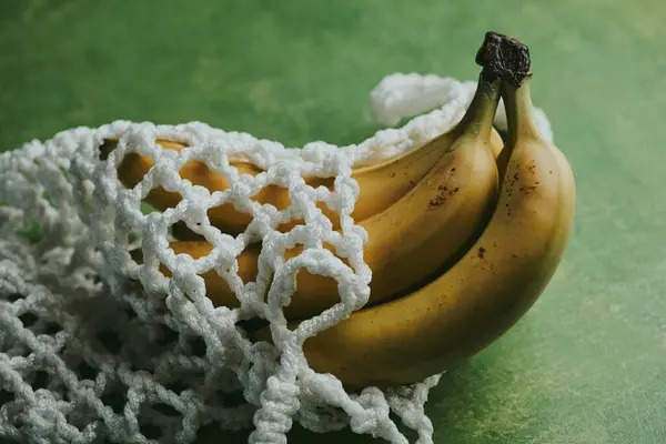 Close-up of bananas in a string bag on a green background