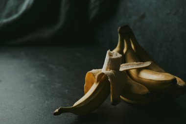 Koyu renk kumaş arka planda bir grup muzun yakın çekimi