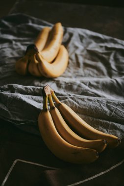 Koyu renk kumaş arka planda bir grup muzun yakın çekimi