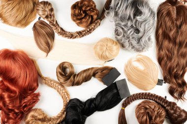 Doğal görünümlü parlak saçlar, bir sürü farklı renk bukleleri ve beyaz arka planda izole edilmiş peruklar.