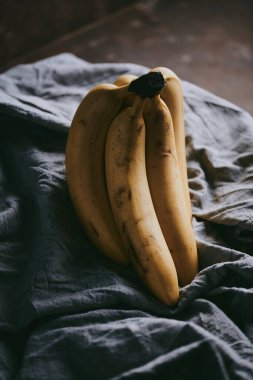 Koyu renk kumaş arka planda bir grup muzun yakın çekimi