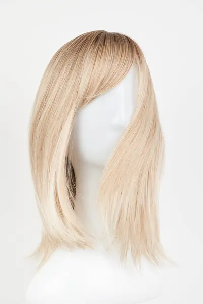Natural looking blonde fair wig on white mannequin head. Middle length hair cut on the plastic wig holder isolated on white backgroun
