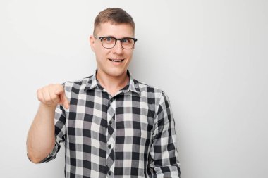 Kendine güvenen bir adamın portresi beyaz stüdyo arka planında izole edilmiş kamerayı işaret eder. Hoş geldin jesti, takımımıza katıl.