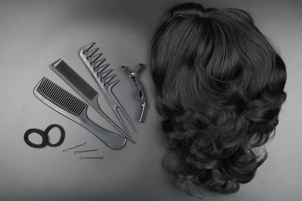 Hairdresser tools close-up isolated on black background. Curls of dark brunette hair and a set of combs, clips, hairpins, hair beauty salon concept