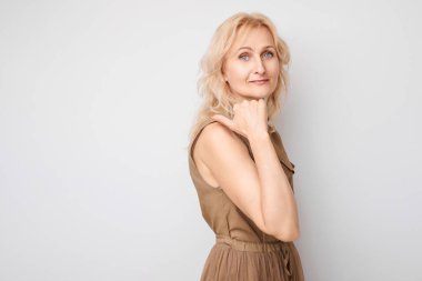 50 yaşında güzel, olgun bir kadın, beyaz stüdyo arka planında izole edilmiş ürün veya metin için boş alan gösteriyor.