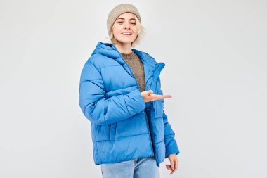 Mavi kışlık ceketli genç bir kadın elinde bir şey tutuyor. Beyaz stüdyo arka grubunda boş bir alan ya da mesaj gösteriyor.