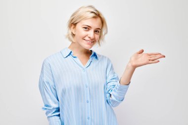 Sarışın genç bir kadın elinde bir şey tutuyor. Beyaz stüdyo arka grubunda boş bir alan ya da mesaj gösteriyor.