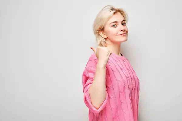 Jonge Blonde Vrouw Roze Trui Wijst Opzij Vinger Waaruit Blijkt — Stockfoto