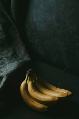 Koyu renk kumaş arka planda bir grup muzun yakın çekimi