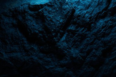 Mavi neon ışıklı siyah taş doku, koyu soyut arkaplan. Doğal mineral kaya detayları kapat, tasarım için kopya alanı olan boş arkaplan