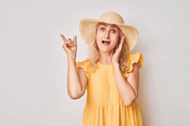 50 yaşında güzel, olgun bir kadın, beyaz stüdyo arka planında izole edilmiş ürün veya metin için boş alan gösteriyor.