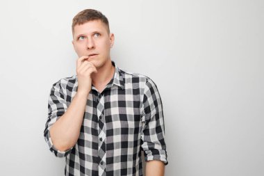 Çeneye dokunan tişörtlü zeki bir adamın portresi şüphelerin beyaz stüdyo arka planında kopya alanı ile izole edildiğini düşünüyor.