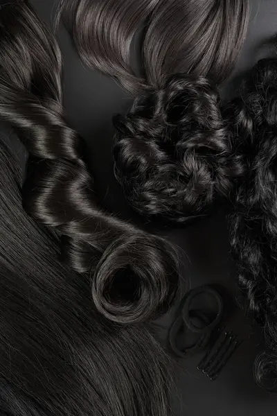 Natural looking shiny hair, bunch of dark brunette colors curls and wigs isolated on black background