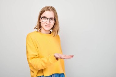 Sarı giysili genç kız elinde bir şey tutuyor. Ürün için boş bir alan ya da beyaz stüdyo arka grubunda izole edilmiş bir mesaj gösteriyor.