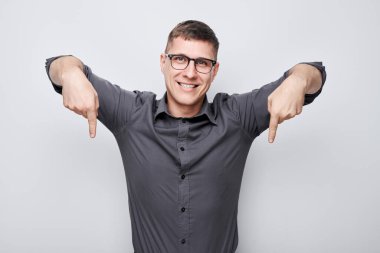 Gözlüklü yakışıklı adam parmağıyla işaret ediyor. Ürün için boş alan ya da beyaz stüdyo arka grubunda izole edilmiş metin gösteriyor.