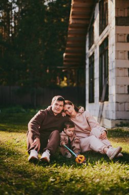Mutlu aile portresi anne ve baba ve oğul güneşli sonbahar gününde birlikte eğleniyor ve eğleniyorlar. Aileler bir rüya ev inşa ediyorlar, ipotek konsepti.