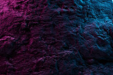 Pembe mavi neon ışıklı siyah taş doku, koyu soyut arkaplan. Doğal mineral kaya detayları kapat, tasarım için kopya alanı olan boş arkaplan
