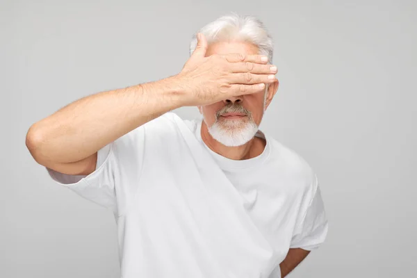 白いスタジオのバックグラウンの手で目を覆う高齢者の肖像画 — ストック写真