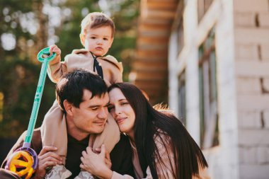 Mutlu aile portresi anne ve baba ve oğul güneşli sonbahar gününde birlikte eğleniyor ve eğleniyorlar. Aileler bir rüya ev inşa ediyorlar, ipotek konsepti.