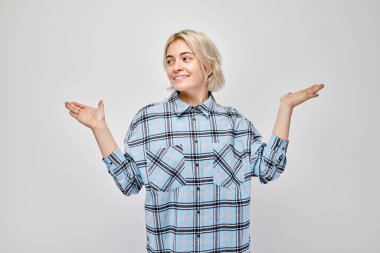 Young blond woman in casual holding something in hand, demonstrating empty space for product or text isolated on white studio backgroun clipart