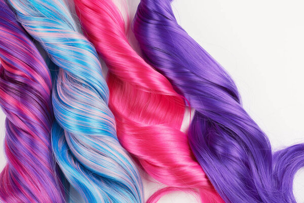 Natural looking shiny hair of different bright colors, cosplay wig on a white background