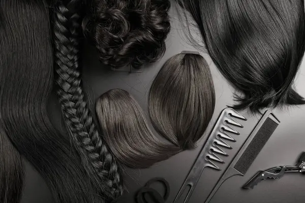 Hairdresser tools close-up isolated on black background. Curls of dark brunette hair and a set of combs, clips, hairpins, hair beauty salon concept