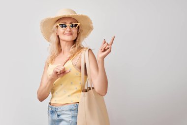 50 yaşında güzel, olgun bir kadın, beyaz stüdyo arka planında izole edilmiş ürün veya metin için boş alan gösteriyor.