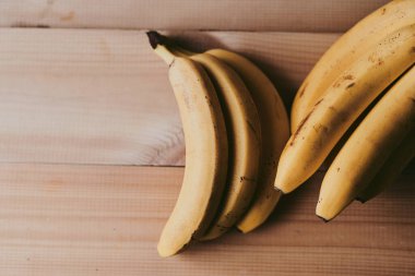 Ahşap mutfak masasında bir grup muzun yakın plan fotoğrafı.