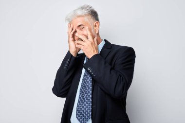 Yaşlı bir adamın portresi eliyle gözlerini kapatıyor, beyaz stüdyoda izole edilmiş parmaklarıyla dikizliyordu.