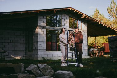 Mutlu aile portresi anne ve baba ve oğul güneşli sonbahar gününde birlikte eğleniyor ve eğleniyorlar. Aileler bir rüya ev inşa ediyorlar, ipotek konsepti.