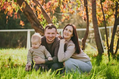 Mutlu aile portresi anne baba ve oğul güneşli bir günde sonbahar parkında birlikte eğleniyor ve eğleniyorlar. Aşk ve sadakat, genç ebeveynler