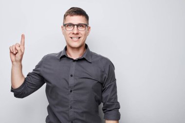 Gözlüklü yakışıklı adam, beyaz stüdyo arka grubunda izole edilmiş ürün ya da metin için boş alan gösteriyor.