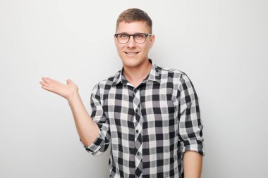 Gözlüklü yakışıklı bir adam elinde bir şey tutuyor. Ürün için boş bir alan ya da beyaz stüdyo arka grubunda izole edilmiş bir mesaj gösteriyor.