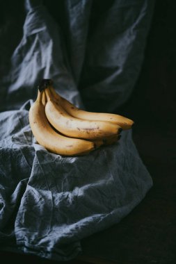 Koyu renk kumaş arka planda bir grup muzun yakın çekimi