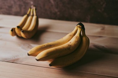 Ahşap mutfak masasında bir grup muzun yakın plan fotoğrafı.