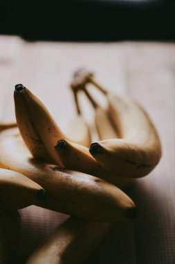 Ahşap mutfak masasında bir grup muzun yakın plan fotoğrafı.