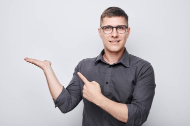 Gözlüklü yakışıklı bir adam elinde bir şey tutuyor. Ürün için boş bir alan ya da beyaz stüdyo arka grubunda izole edilmiş bir mesaj gösteriyor.