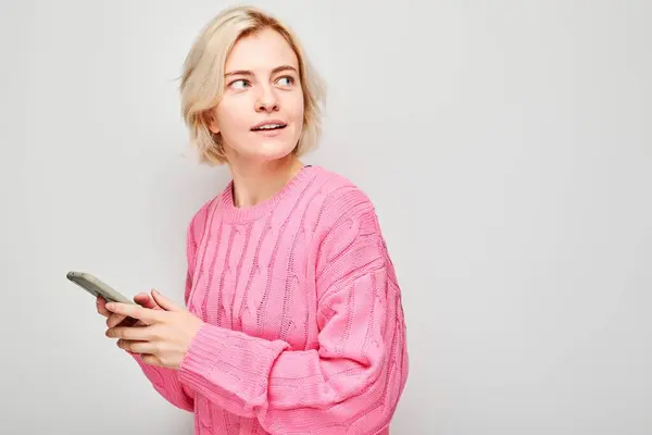 Портрет Молодой Блондинки Розовом Свитере Держащей Руке Мобильный Телефон Счастливым — стоковое фото