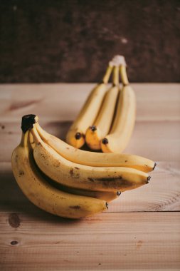 Ahşap mutfak masasında bir grup muzun yakın plan fotoğrafı.