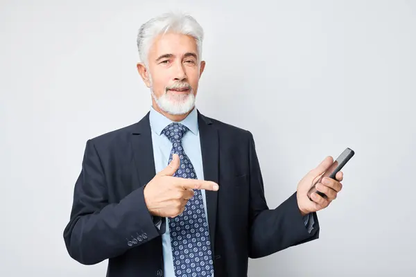 Portrait of elderly businessman in suit showing blank mobile phone screen with excited face. Person with smartphone isolated on white backgroun