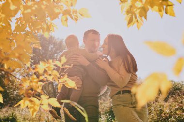 Mutlu aile portresi anne baba ve oğul güneşli bir günde sonbahar parkında birlikte eğleniyor ve eğleniyorlar. Aşk ve sadakat, genç ebeveynler