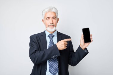 Takım elbiseli yaşlı işadamının portresi heyecanlı yüzüyle boş bir cep telefonu ekranı gösteriyor. Akıllı telefonu olan kişi beyaz grupta izole edildi