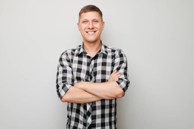 Kollarını göğsünde kavuşturarak sevinçle gülümseyen portre adam beyaz stüdyo arka planında izole edilmiş, reklam afişi.